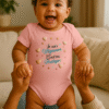 Bébé souriant debout, porté par un adulte, vêtu du body rose Lynonis "Je suis mignonne, c’est ma stratégie !" décoré de cœurs et d’étoiles